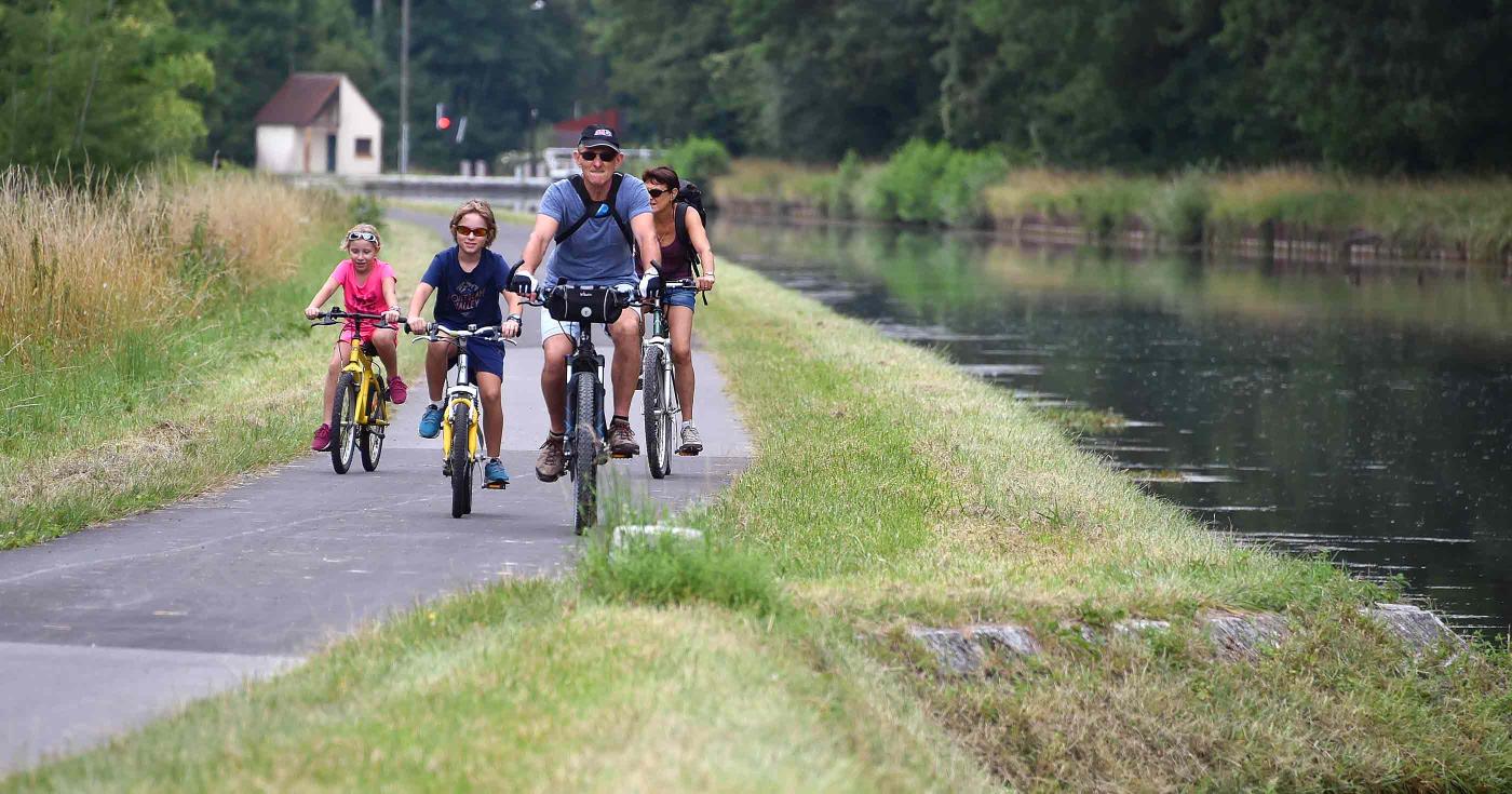 Balade à vélo d'un couple avec leurs deux enfants sur les bords d'un canal